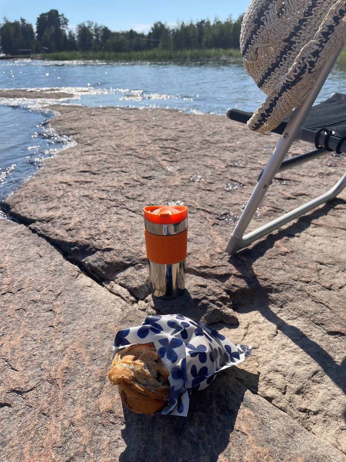 Bivaxpåse Alva med bullar på en klippa med sjö bakom
