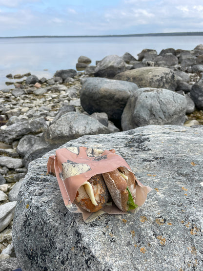 Deli bivaxpåse med smörgåsar i som ligger på en klippa 